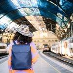a woman with a backpack and hat standing in a train station